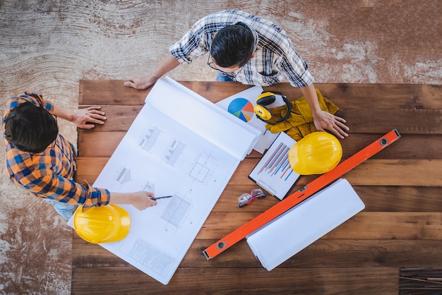 Foto visão de alto ângulo de uma equipe de engenheiros de construção e dois arquitetos na reunião para projetar a construção e discutir o desenho da casa e o planejamento da construção na área de construção.