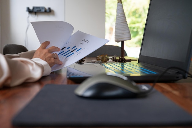 Visão de ângulo baixo de uma empresária revisando os documentos do relatório de negócios de 2022 e planejando uma mesa de trabalho decorada de férias.