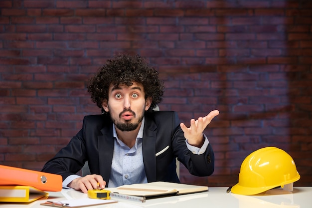 visão de close-up engenheiro masculino sentado atrás do local de trabalho em terno empreiteiro trabalho negócios construtor agenda trabalho dentro de casa