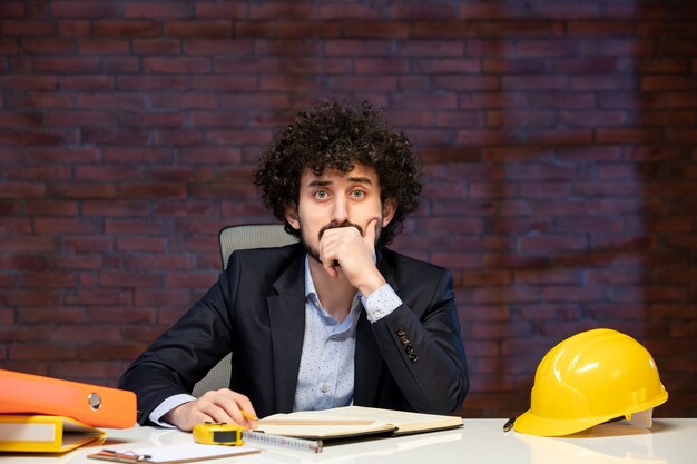 Foto visão de close-up estressado engenheiro masculino sentado atrás do local de trabalho em terno empreiteiro negócios trabalho corporativo construtor de agenda de trabalho