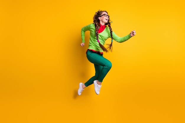 Visão de corpo inteiro de tamanho corporal de uma garota atraente e alegre, pulando motivação em execução isolada fundo de cor amarela brilhante