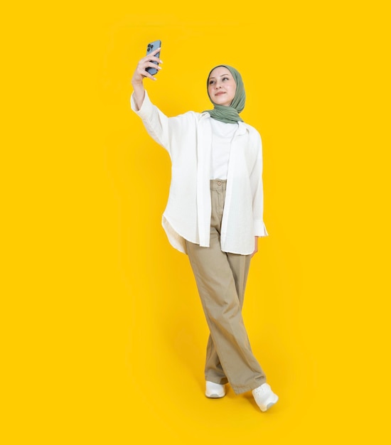 visão de corpo inteiro jovem muçulmana caucasiana em hijab tirando selfie Use roupa casual