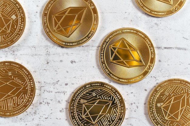 Visão detalhada de cima para baixo, EOS comemorativa dourada - criptomoeda EOSIO - moedas na placa de pedra branca