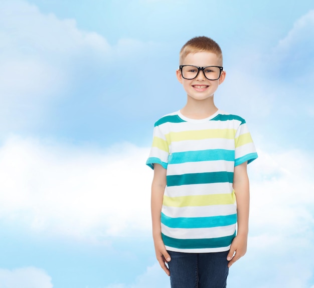 visão, educação, infância e conceito de escola - menino sorridente em óculos sobre o céu azul com fundo de nuvens brancas