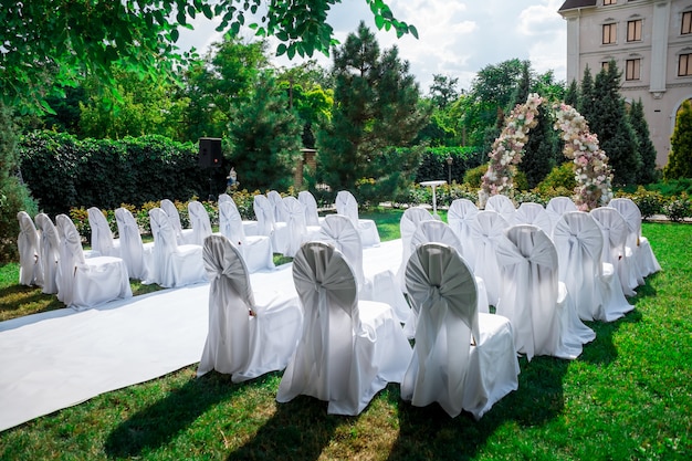 visão geral da decoração da cerimônia de casamento no jardim no ar. decoração de casamento um arco feito de flores frescas, cadeiras cobertas para convidados