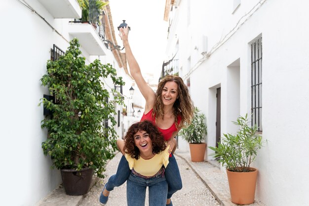 Visão horizontal das namoradas do casal dando um passeio nas costas rindo. Conceito de viagens no verão.