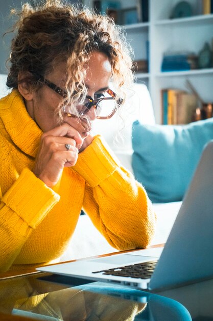 Foto visão lateral concentrada mulher adulta madura agradável olhando para a tela do computador mulher de meia-idade feliz navegando na web informações encomendando comida on-line conversando em redes sociais jogando jogos