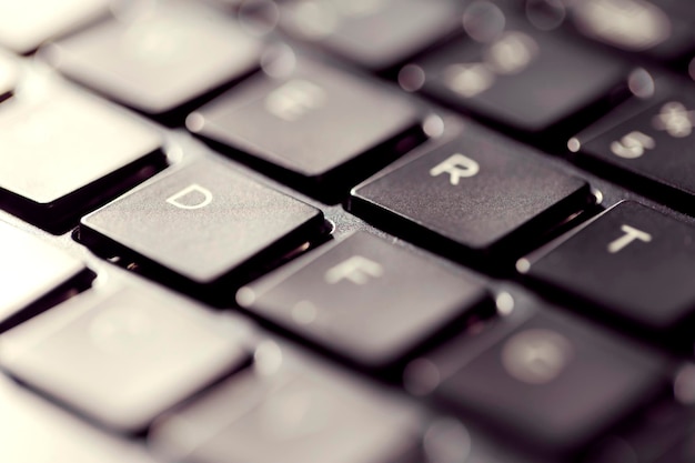 Visão macro dos botões pretos do teclado do laptop contra a luz de fundo