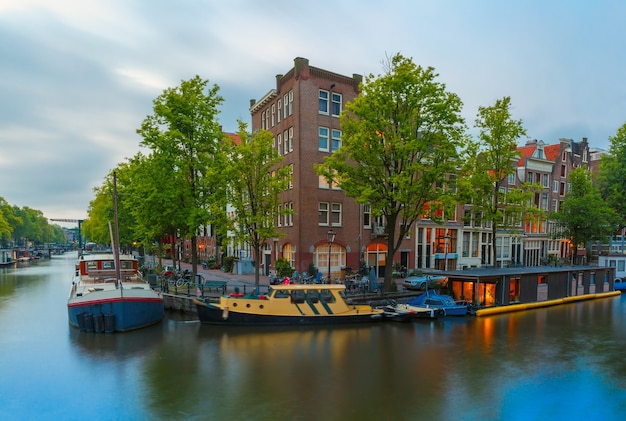 Visão noturna da cidade do canal de Amsterdã, ponte e casas típicas, barcos e bicicletas, Holanda, Holanda.