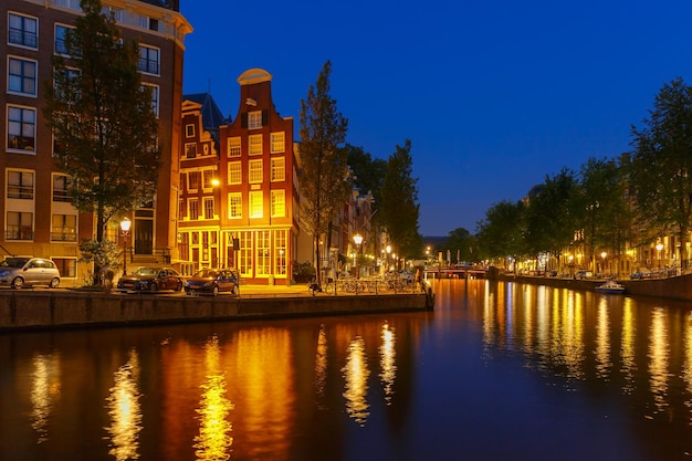 Visão noturna da cidade do canal de Amsterdã, ponte e casas típicas, barcos e bicicletas, Holanda, Holanda.