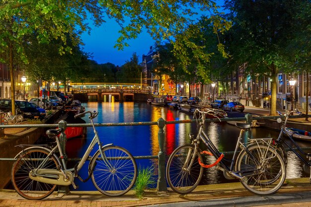 Visão noturna da cidade do canal e da ponte de amsterdã, barcos e bicicletas, holanda, holanda.