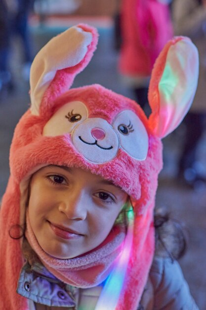 Visão noturna de uma menina sorridente com um chapéu rosa com orelhas iluminadas no natal em toledo, espanha