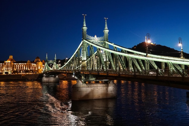 Visão noturna de uma ponte da liberdade Szabadsag escondida sobre o rio Danúbio em BudapesteHungria