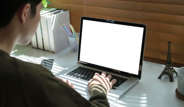 Visão por cima do ombro do freelancer masculino trabalhando on-line digitando e-mail comercial no computador portátil