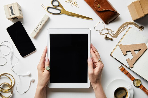 Visão recortada da mulher segurando o tablet digital nas mãos perto do estojo de joias de fones de ouvido para smartphone