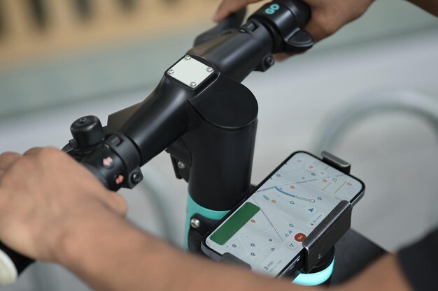 Visão recortada das mãos do homem passando o aplicativo móvel enquanto se prepara para andar de scooter
