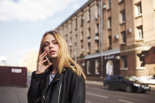 Visão recortada de mulher loira com celular na rua perto do prédio