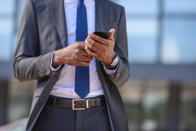 visão recortada de um empresário afro-americano usando smartphone na rua