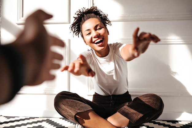 Visão recortada do fotógrafo e da mulher afro-americana rindo Garota negra feliz posando com as mãos estendidas