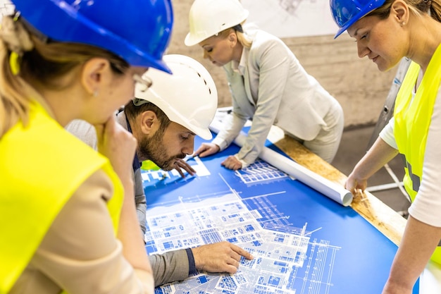 Foto visão superior de arquitetos e engenheiros no canteiro de obras analisando a planta e o plano do projeto