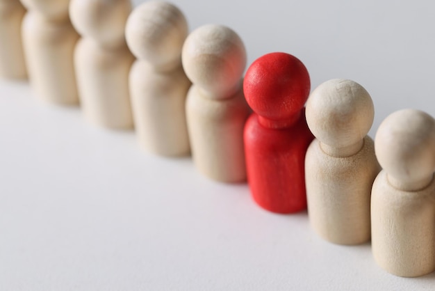 Visão superior de uma figura vermelha em fila entre figuras de pessoas de madeira individualidade liderança única