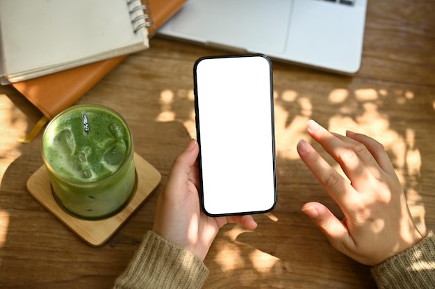 Visão superior de uma mulher usando seu smartphone enquanto trabalha remotamente e relaxa em um café