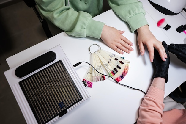 Visão superior do mestre de manicure trabalhando com cliente do sexo feminino no salão de beleza manicure faz unha de mulher