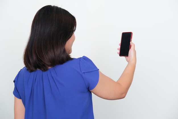 Foto visão traseira da mulher asiática sorrindo enquanto olha para o celular que ela segura