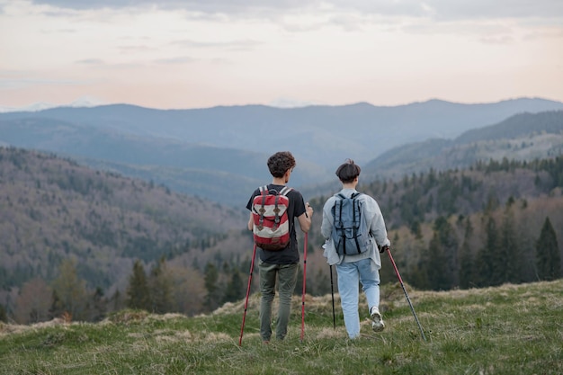 Visão traseira de alguns viajantes com bengalas caminhando no alto das montanhas Beleza da natureza