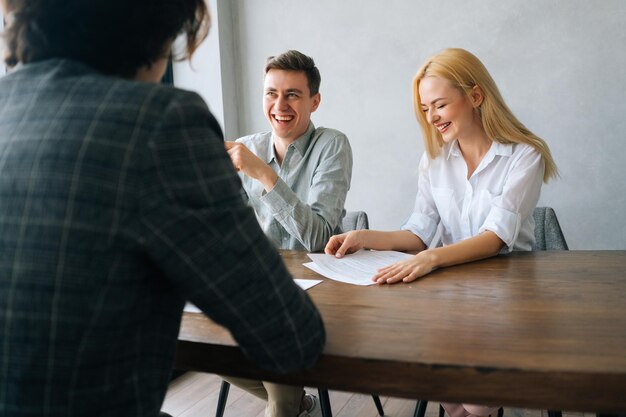 Visão traseira de headhunters masculinos e femininos alegres verificando currículo de candidato a homem irreconhecível fazendo perguntas durante entrevista de emprego com candidato a emprego masculino Conceito de recrutamento de recursos humanos