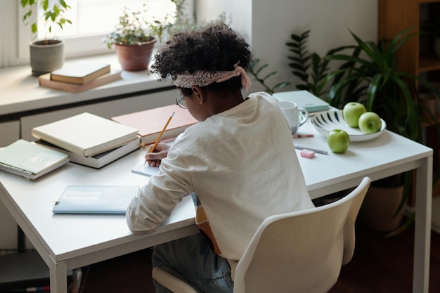 Visão traseira de um ensaio de redação de aluno afro-americano diligente