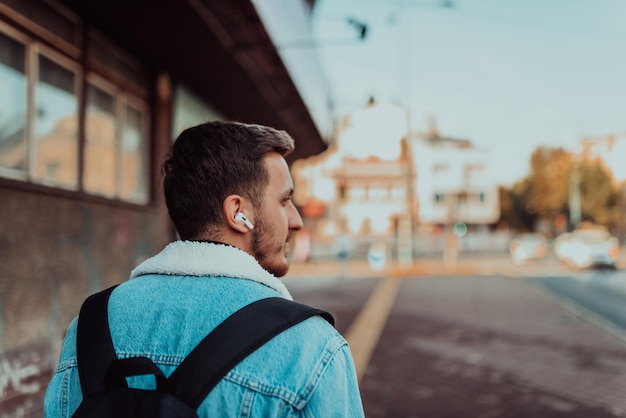 Visão traseira de um homem ouvindo música e falando em fones de ouvido sem fio no centro da cidade