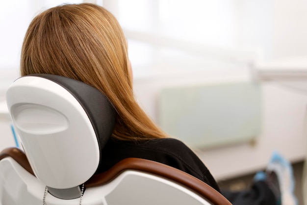 Visão traseira de uma mulher sentada em uma cadeira odontológica Cadeira odontológica confortável e espaçosa para consultório odontológico