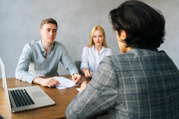 Visão traseira do candidato masculino irreconhecível apresentando durante entrevista de emprego falando sobre experiência de trabalho recrutadores entrevistando gerentes de RH