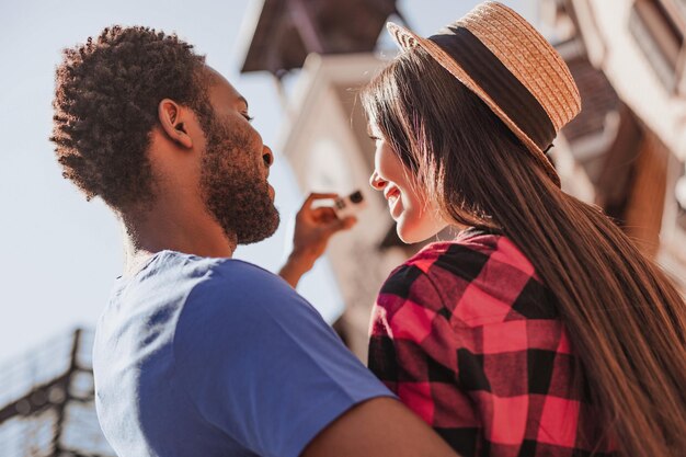 Visão traseira do homem afro-americano e da mulher asiática tirando foto selfie na câmera de ação ao ar livre