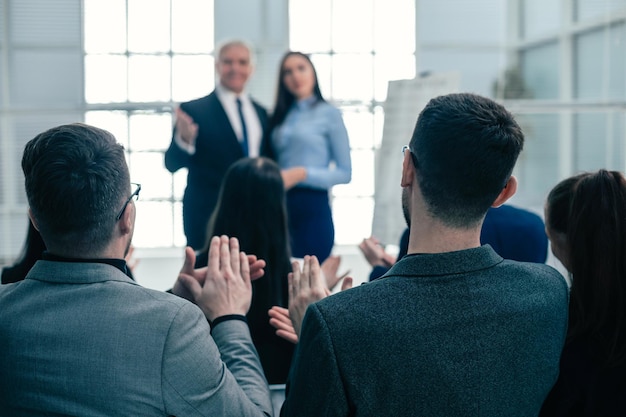 Visão traseira. funcionários da empresa aplaudindo em uma reunião de trabalho. conceito de sucesso