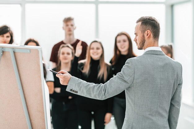 Visão traseira. gerente sério apontando para o flipchart. negócios e educação