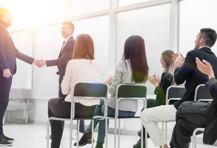 Foto visão traseira. grupo de jovens sentados em cadeiras na sala de conferências