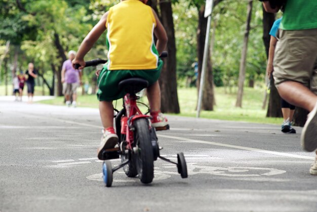 Foto visão traseira seção baixa de menino andando de bicicleta na estrada