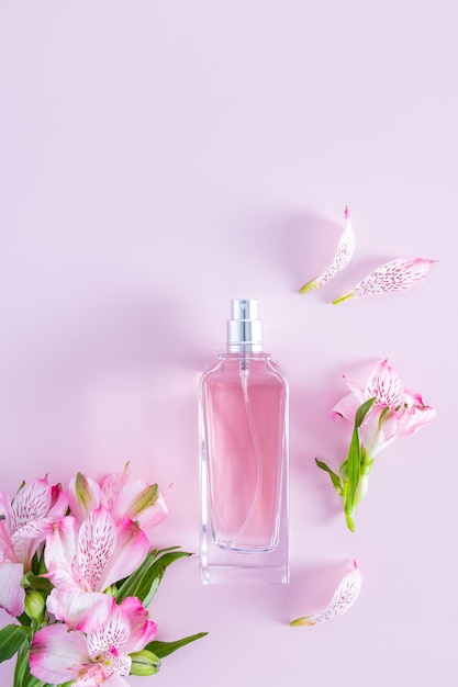 Visão vertical da garrafa com uma fragrância floral de primavera de perfume feminino delicadas flores cor de rosa e botões de fundo lilás um espaço de cópia