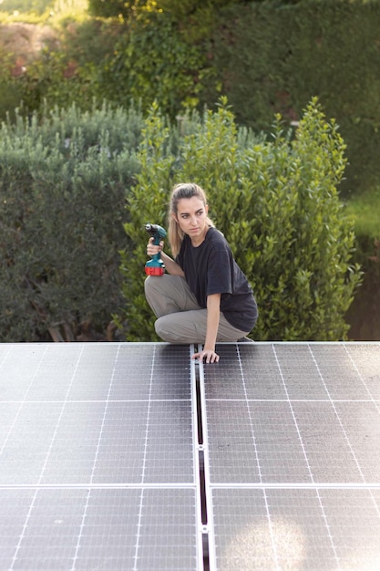 Visão vertical da jovem engenheira trabalhando no telhado solar para serviço de manutenção