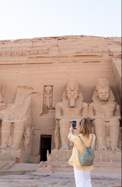 Visão vertical da mulher turista para trás tirando fotos para mídia social para o templo de Abu simbel no Egito