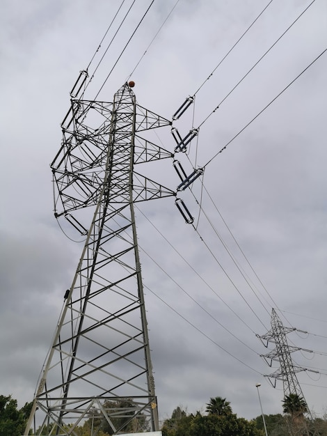 Visão vertical de uma torre de energia elétrica com céu com nuvens.