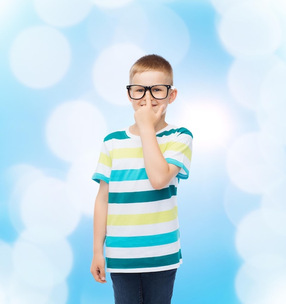 Vision, Bildung und Schulkonzept - lächelnder kleiner Junge mit Brille auf blauem Hintergrund