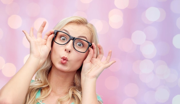 visión, educación y concepto de la gente - mujer joven feliz o anteojos de niña adolescente haciendo cara de pez graciosa sobre fondo de luces de vacaciones rosadas