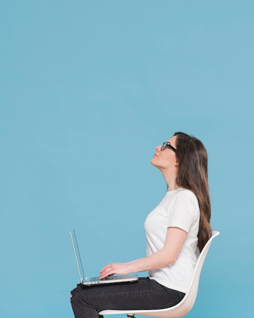 Visión lateral de una mujer con una computadora portátil en el regazo