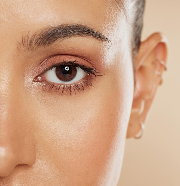 Visión ocular y belleza con una mujer modelo de primer plano en el estudio sobre un fondo beige para el cuidado de los ojos o la piel Cosméticos Zoom y bienestar con una mujer posando para mostrar su ceja o pupila