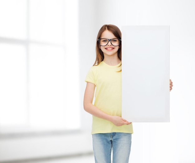 visión, salud, publicidad y concepto de personas - niña sonriente que usa anteojos con tablero blanco en blanco