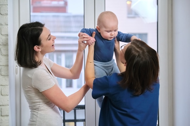 Visita de médico pediatra a domicilio, madre con hijo de siete meses hablando con médico. Examen de salud infantil y puericultura hasta un año