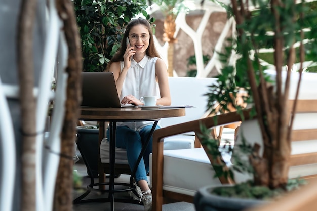 Visitante de un acogedor cibercafé hablando por un teléfono inteligente